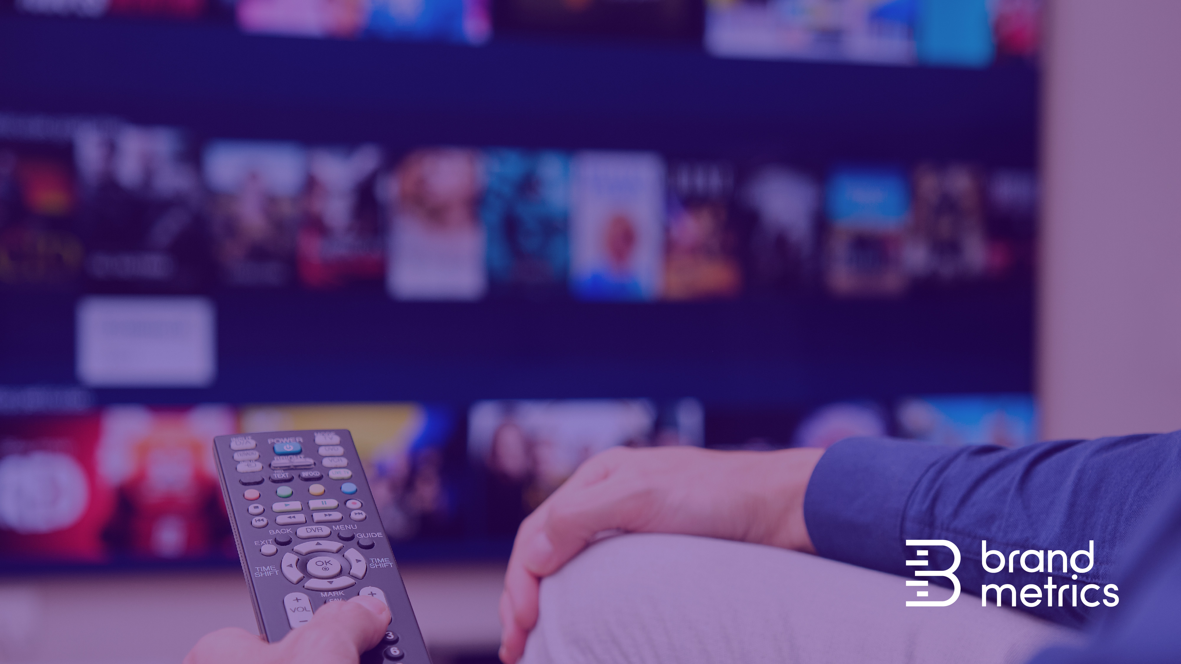 Man holding a remote control in front of a television